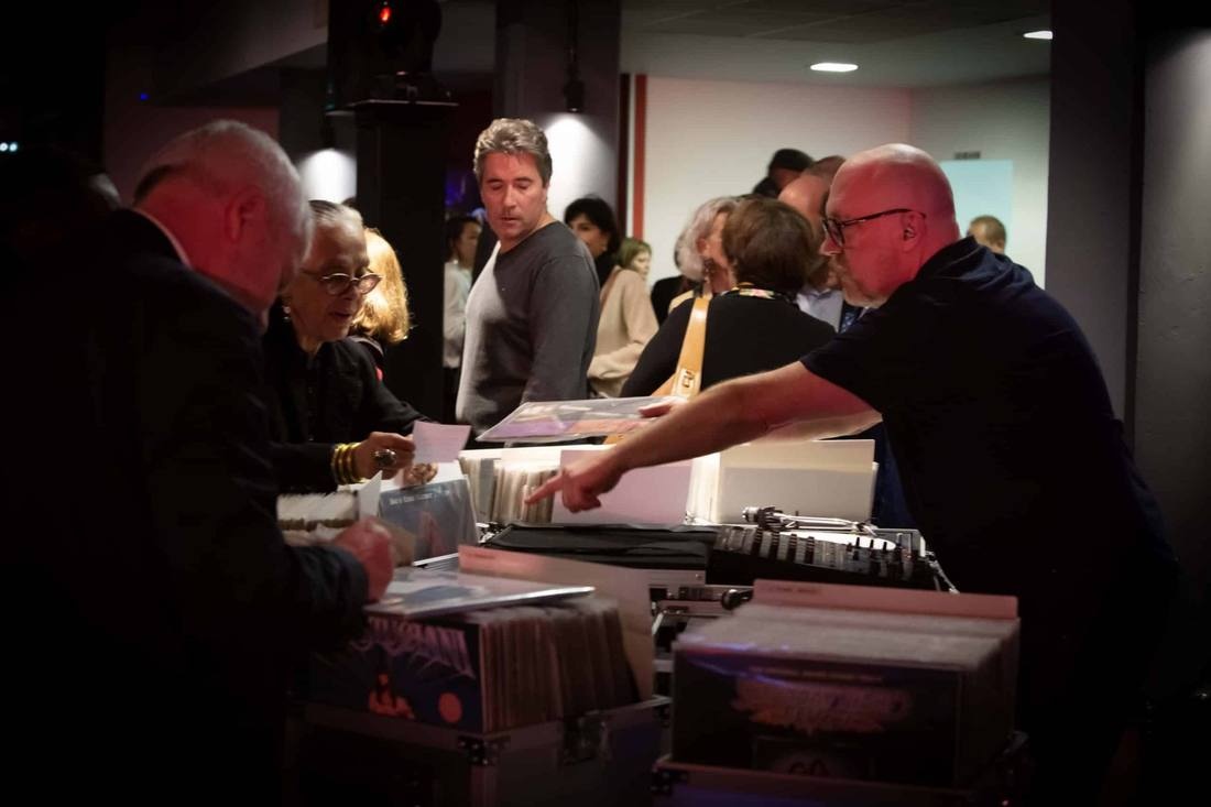 Convives parcourant les bacs à vinyles — vin d'honneur